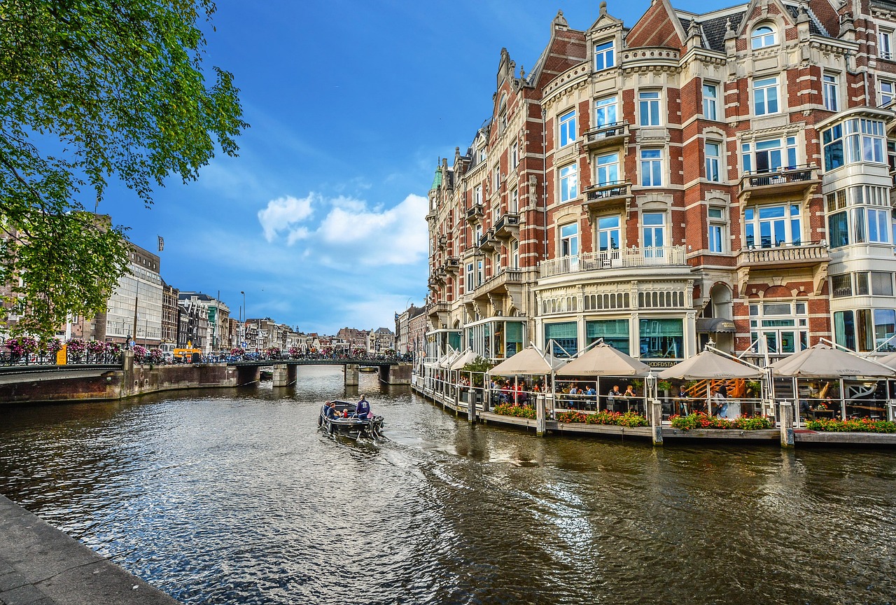 Amsterdam canal with a boat passing a grand hotel