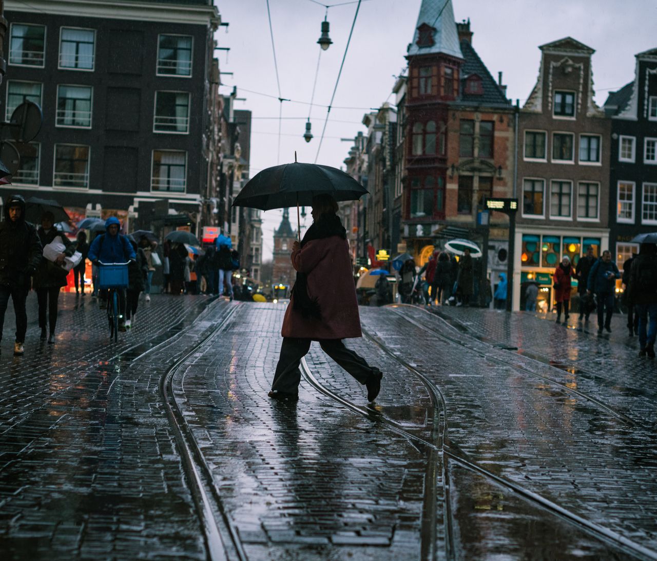 A rainy Dutch street with a pedestrian under an umbrella