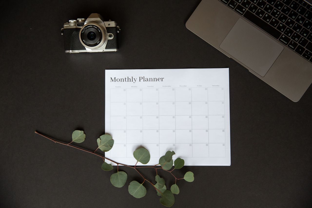 Monthly planner next to a laptop and camera