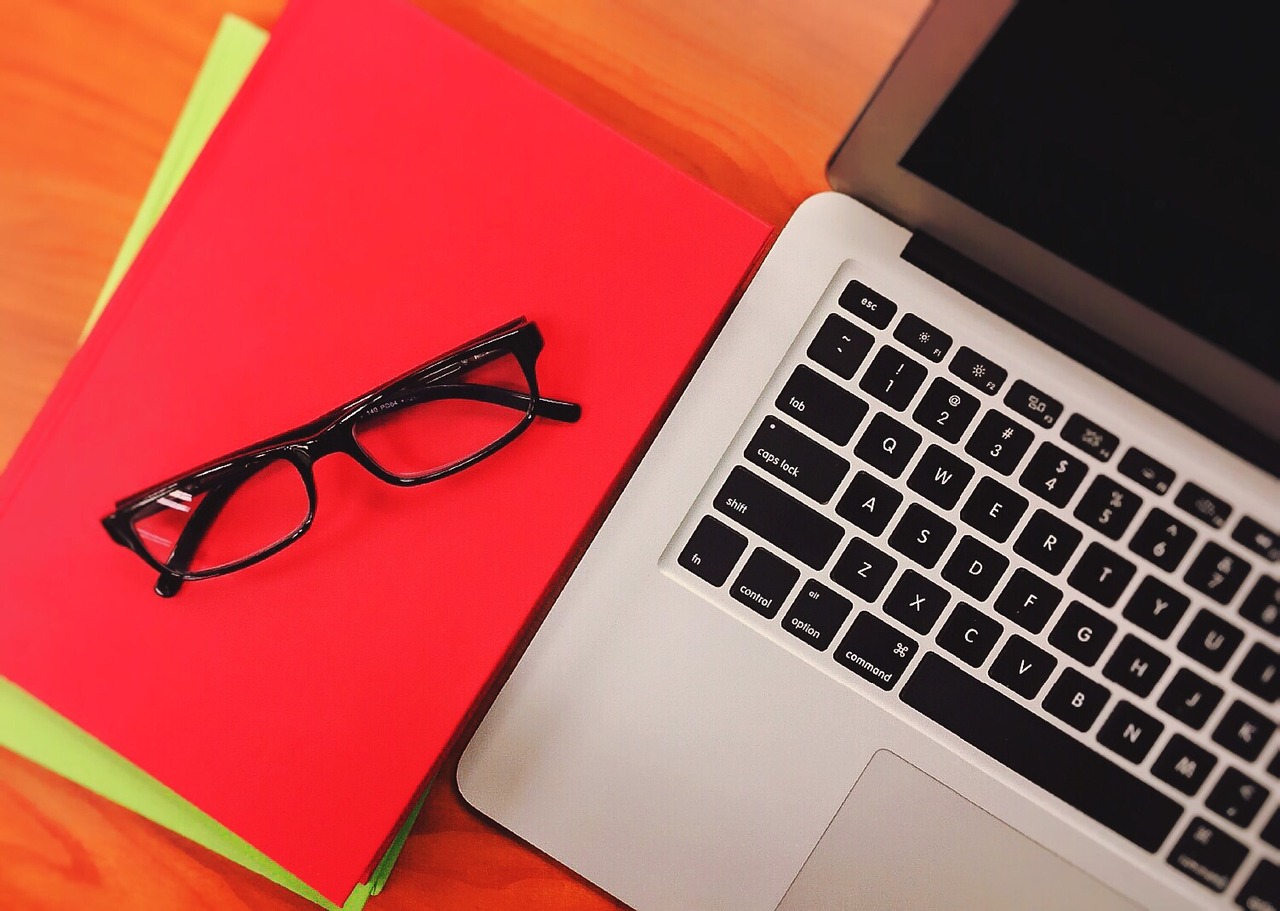 Notebook and glasses next to a laptop
